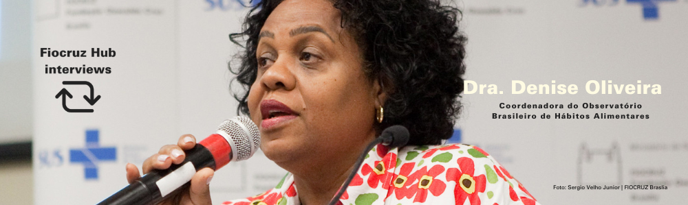 Woman speaking into a microphone, banner. - Fiocruz