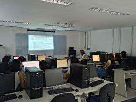 Clase con alumnos en estaciones de computadora.