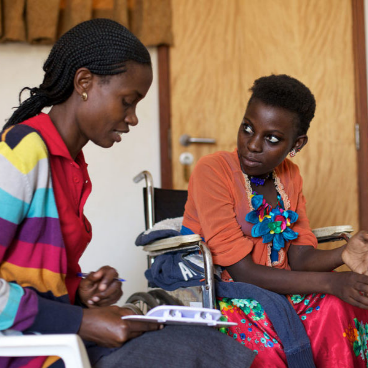 A girl in a wheelchair talks to a healthcare worker in Ghana