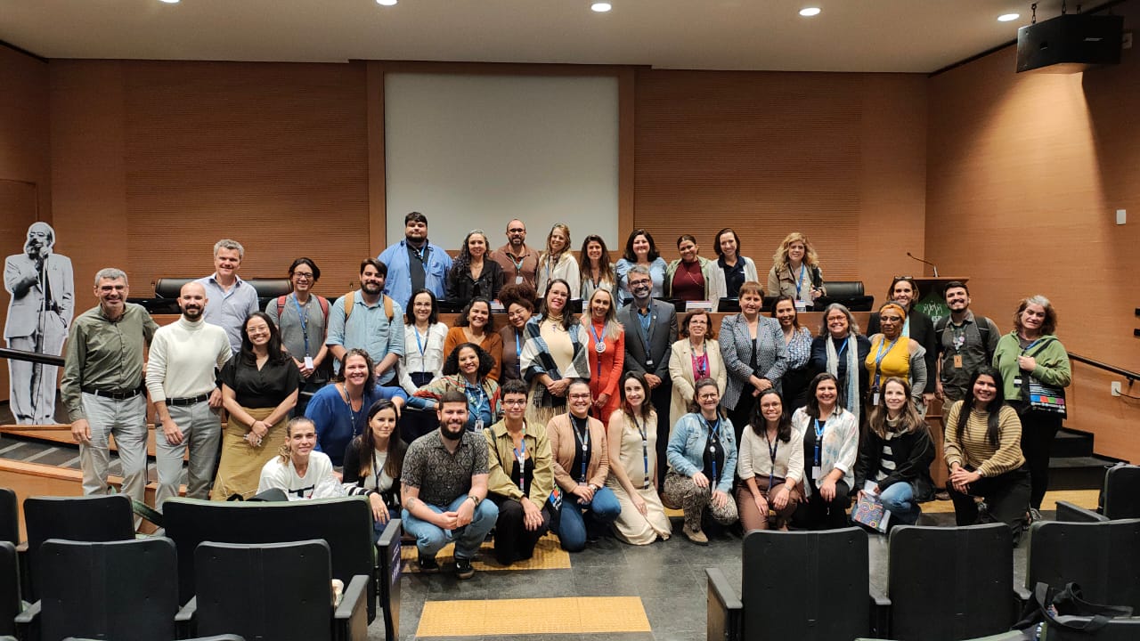 Foto de grupo com participantes do evento em audit&oacute;rio.